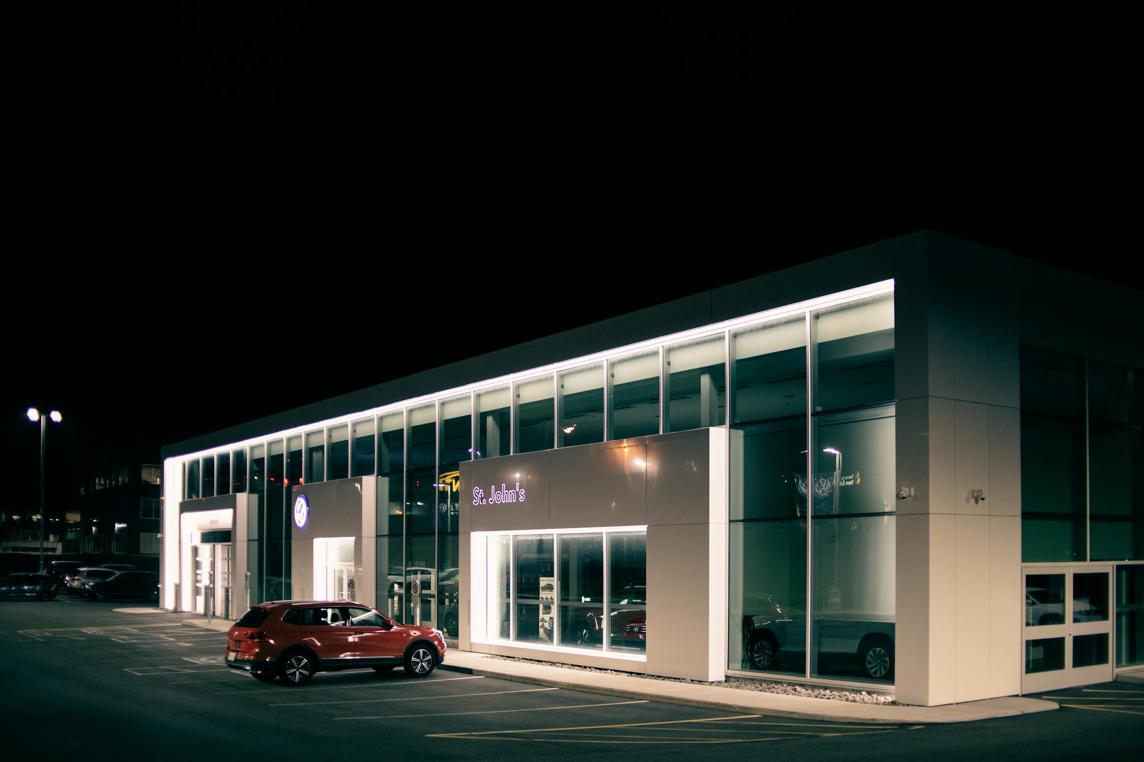 Car parked near building with glowing lights at night